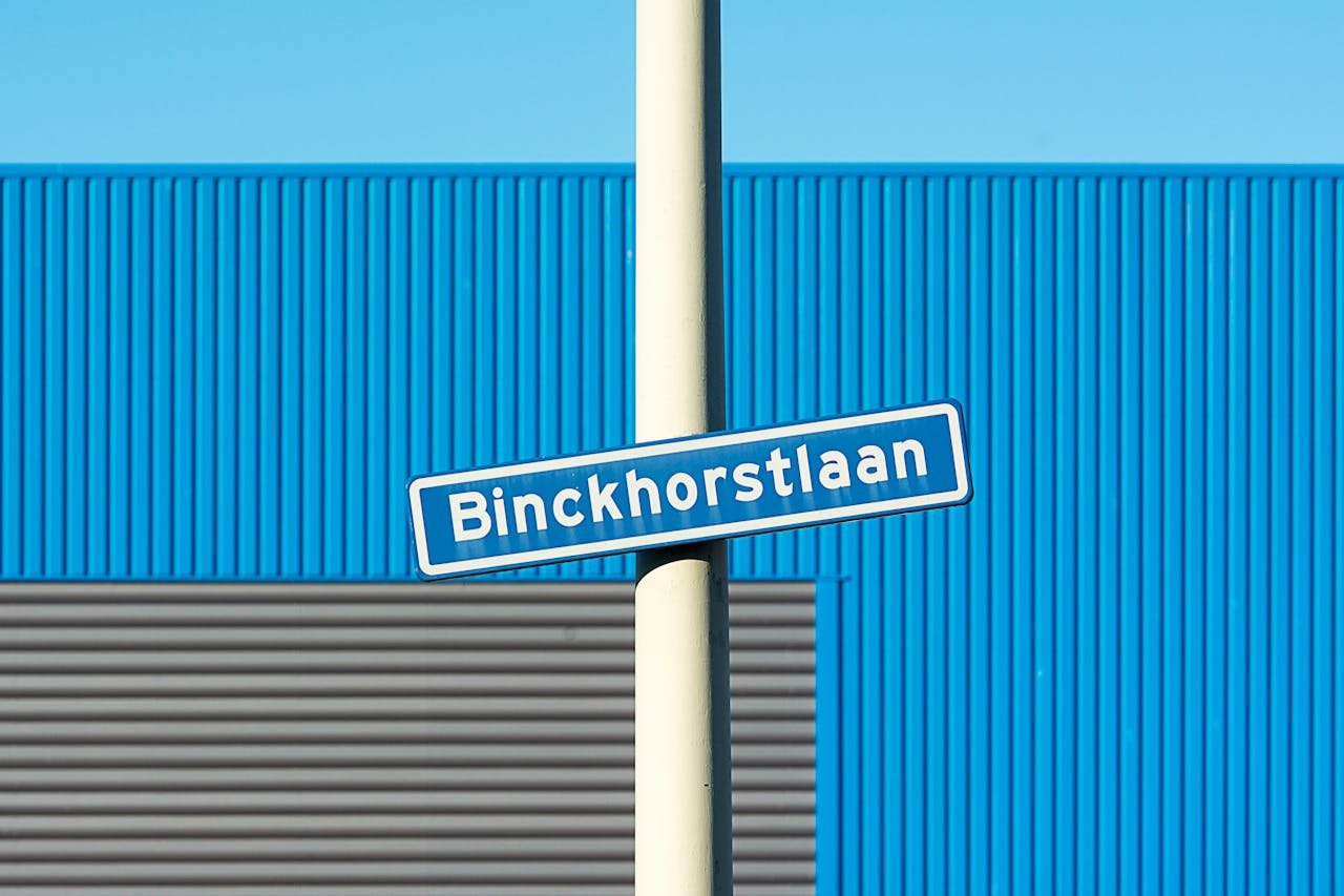Street sign of Binckhorstlaan with blue and grey industrial building background.