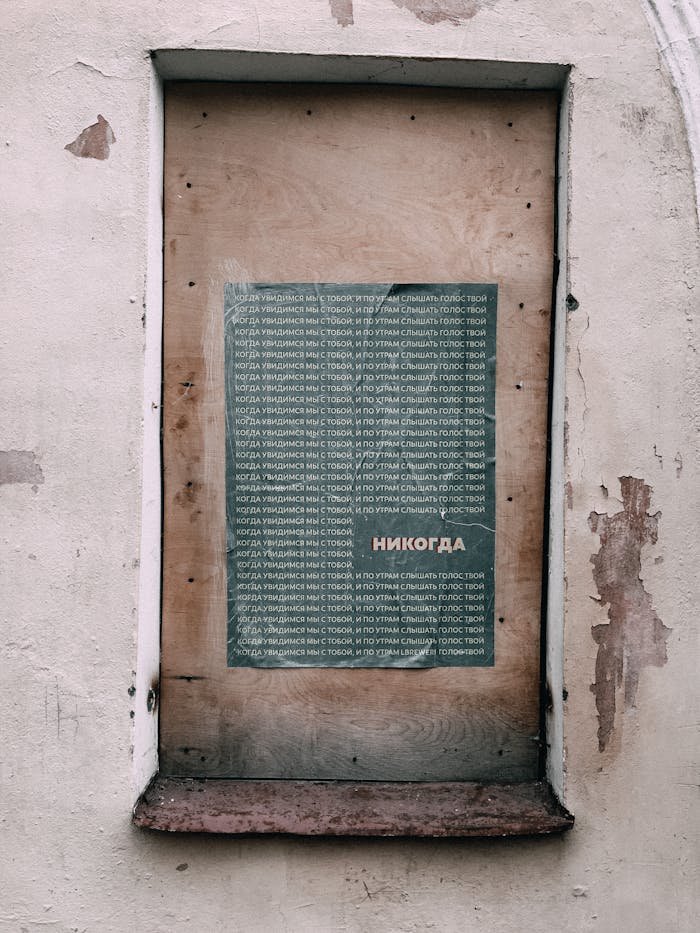 Atmospheric bricked-up window featuring a Russian text poster, evoking urban decay.